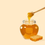 Jar of golden honey with a honey dipper and honeycomb on the side, showcasing rich texture and natural sweetness of Hero Honey